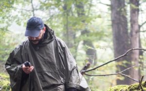 Man in woods using satellite phone