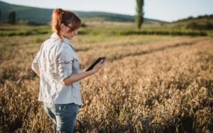 Woman standing in field using an internet-connected device