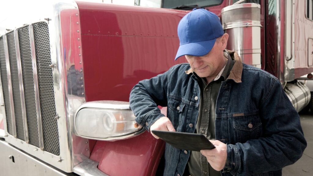 trucker using tablet beside semi