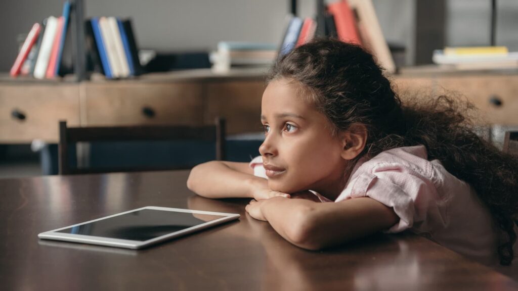 Child sitting at table with iPad