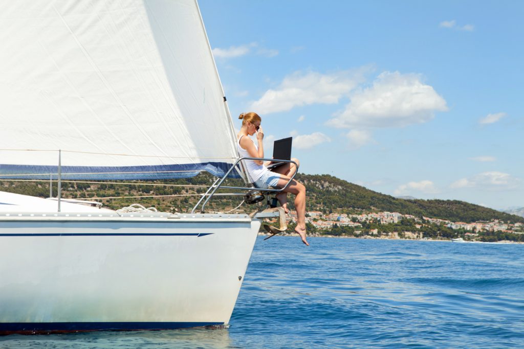 Woman with laptop computer on sailing yacht.