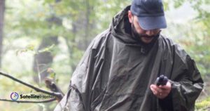 Man in woods using satellite phone