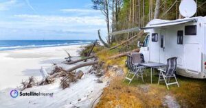 rv parked next to a beach and water with a satellite dish on top