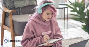 woman with pink hair wearing teal headphones working at home